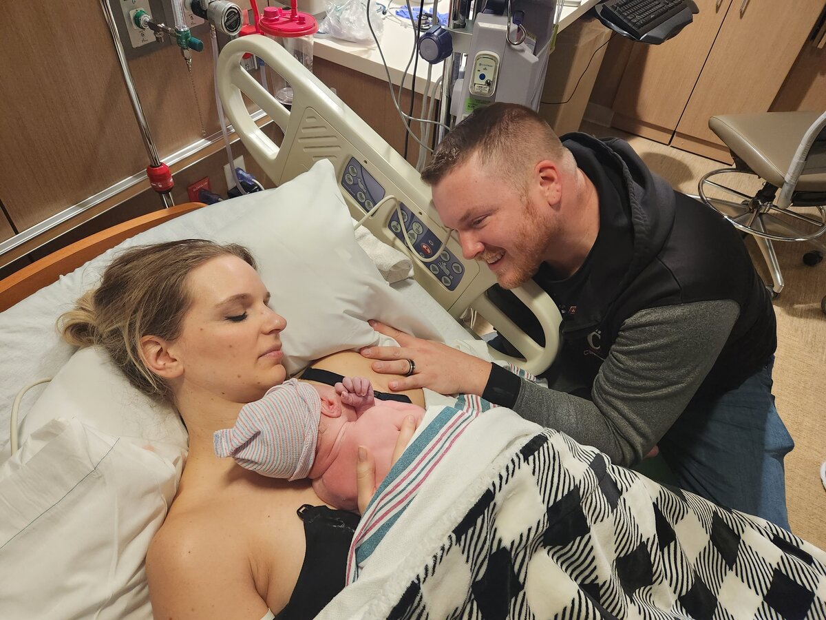couple holding newborn baby in hospital bed
