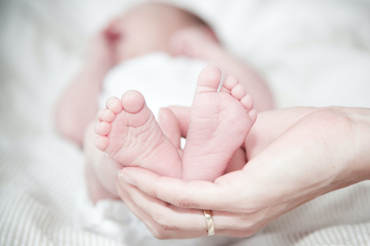 A hand holding a baby's feet